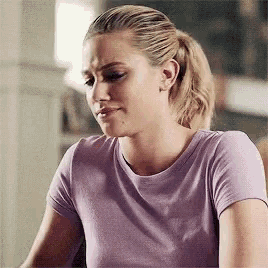 a woman in a purple t-shirt is sitting at a table with her eyes closed and a ponytail .