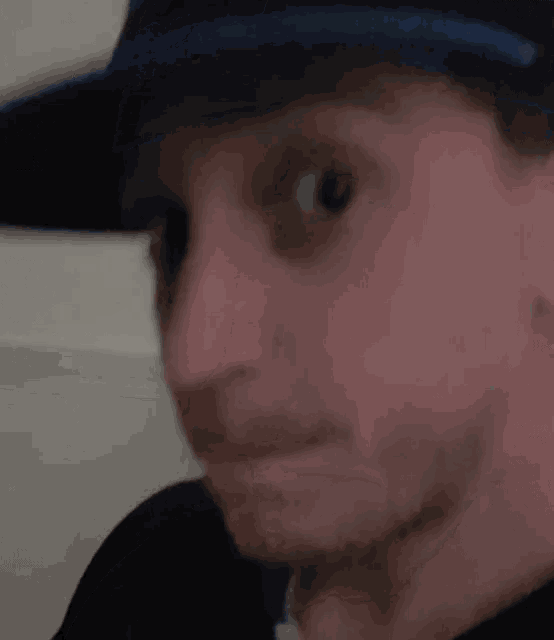 a man wearing a hat is making a funny face and looking at the camera .