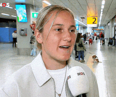 a woman is talking into a nos microphone at an airport