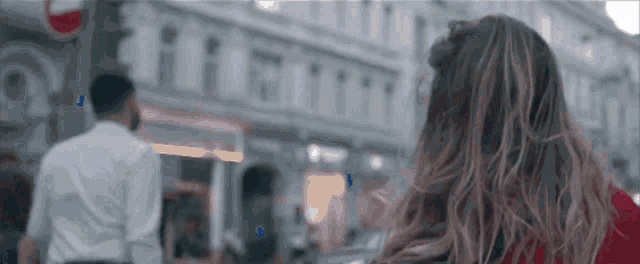 a woman in a red shirt is walking down a city street