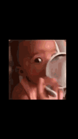 a baby in a pink tank top is making a funny face and looking at the camera .