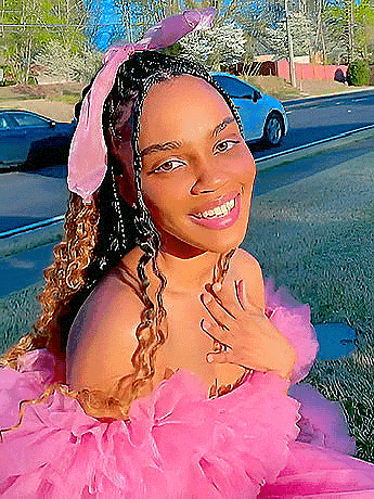 a woman wearing a pink dress and a pink headband is smiling for the camera .