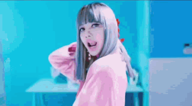 a woman in a pink shirt is standing in front of a blue wall and making a funny face .
