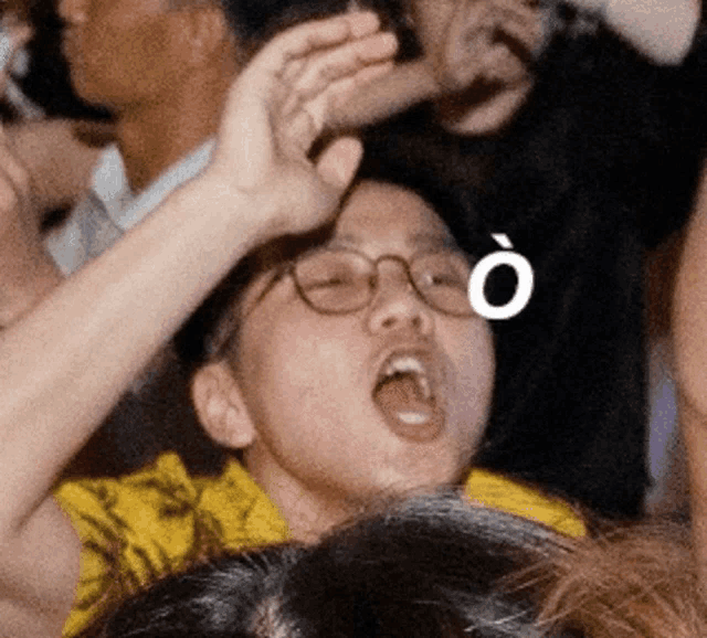 a man wearing glasses and a yellow shirt is making a funny face