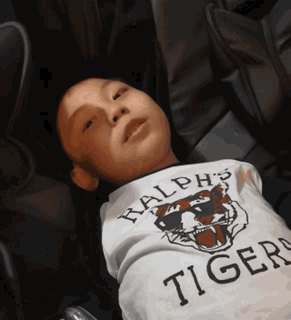 a young boy wearing a shirt that says ralph 's tigers on it
