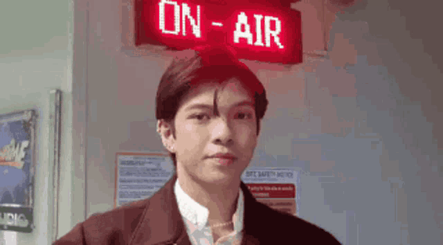 a man is standing in front of a red sign that says on air .