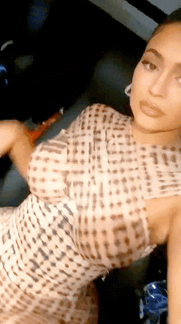 a woman in a leopard print dress is taking a selfie in the back seat of a car