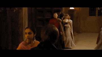 a group of people are standing in a room and a woman is standing in front of them .