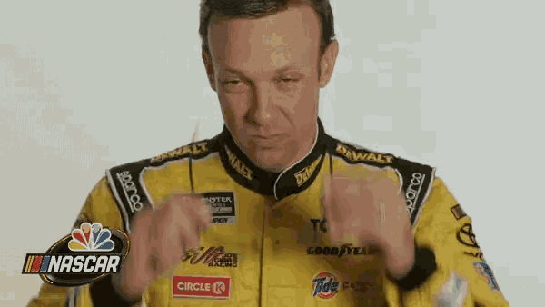 a man in a yellow racing suit is making a funny face .