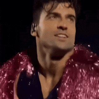 a close up of a man wearing a pink jacket and a black shirt .
