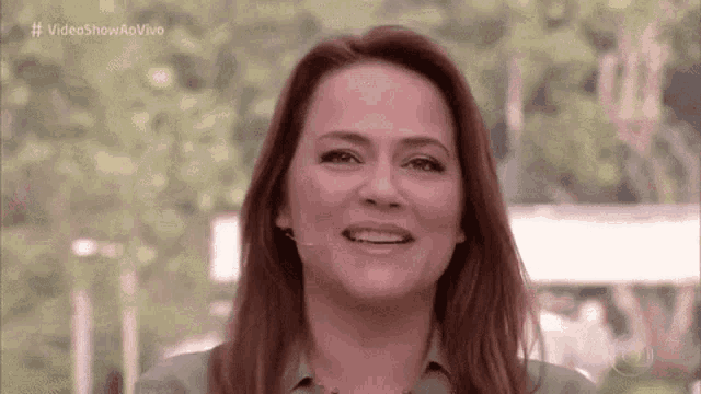 a woman with long red hair is smiling for the camera .