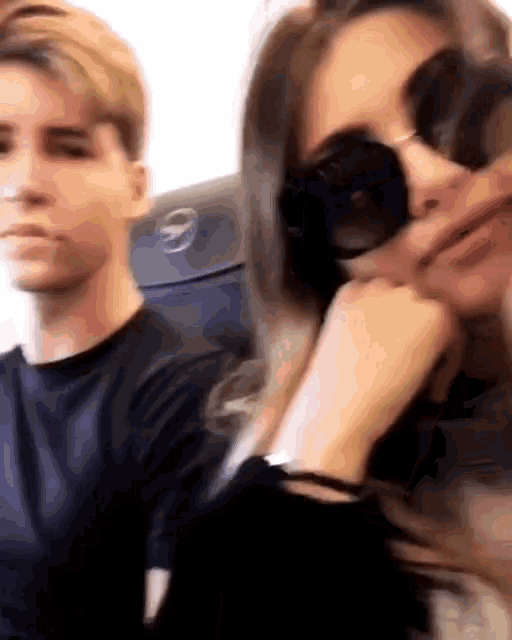 a woman wearing sunglasses is sitting next to a man