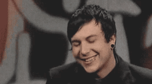 a man with piercings in his ears is smiling with his eyes closed .