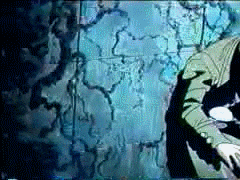 a man in a green jacket stands in front of a blue wall