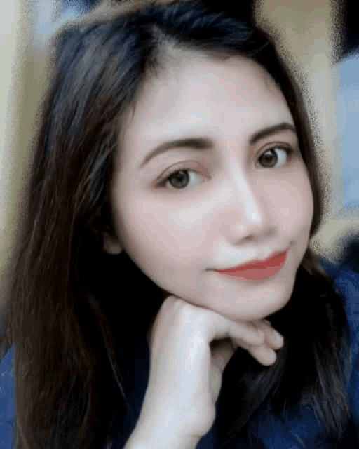 a woman with a hand on her chin looks at the camera