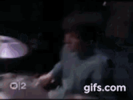 a man is playing drums in a dark room in front of a drum set .