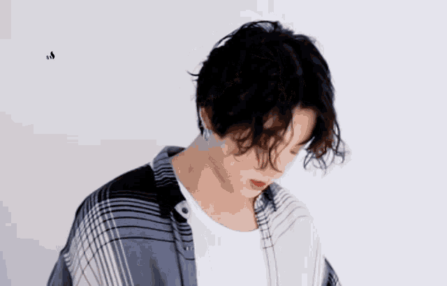 a man with curly hair wearing a plaid shirt