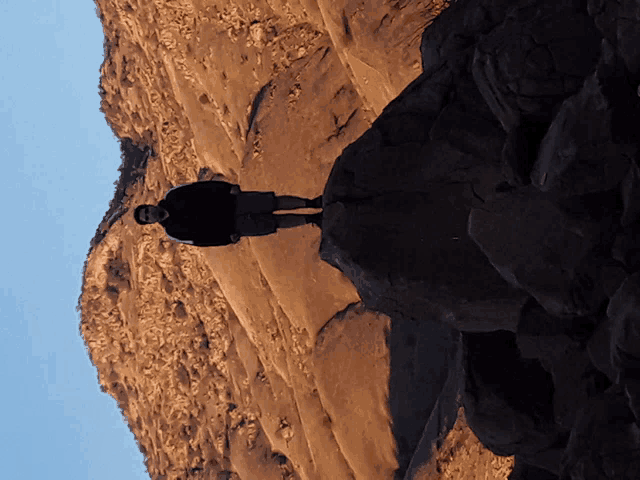 a man standing on a rocky cliff with a blue sky in the background