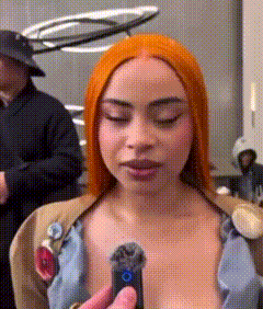 a woman with red hair is holding a remote control and looking at it .