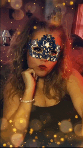 a woman wearing a blue and gold mask with rhinestones on it