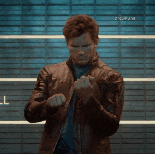 a man in a leather jacket stands in front of a wall with the words brown unit on it