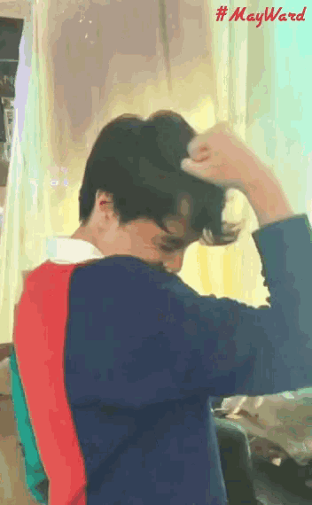 a man adjusts his hair in front of a sign that says # mayward