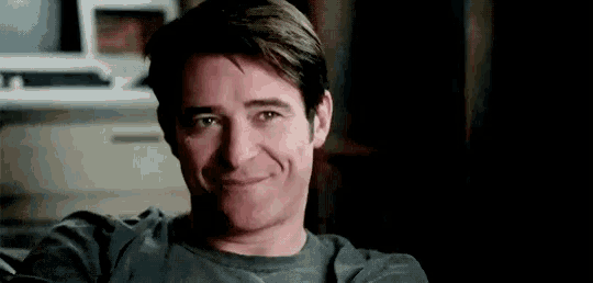 a man is smiling while sitting on a couch .