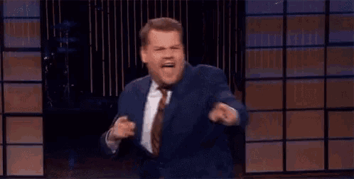 a man in a suit and tie is dancing on a stage while giving a speech .