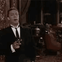 a man in a tuxedo and tie is holding a gun .