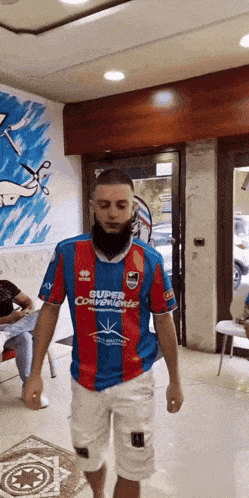 a man in a blue red and white jersey that says super conveniente on it
