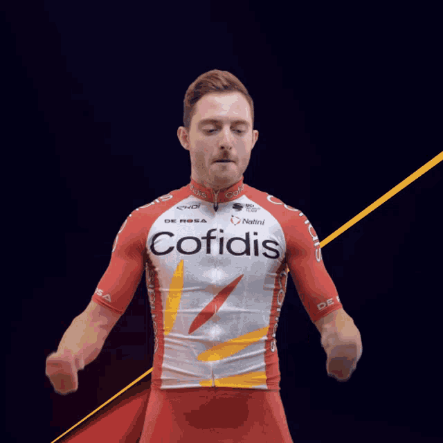 a man wearing a red and white cofidis jersey holds his fist in the air