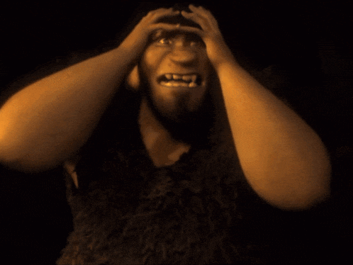 a cartoon character with fangs is holding his head in pain