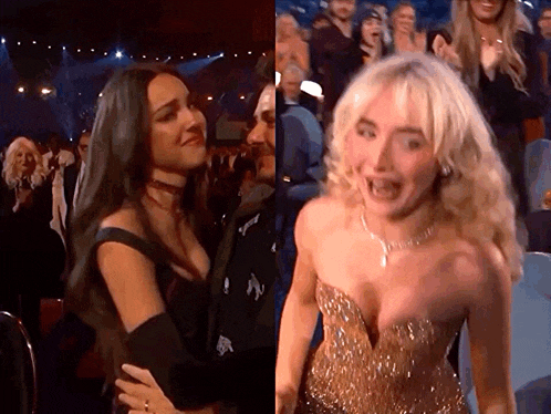 two women are standing next to each other in front of a crowd at a awards show .