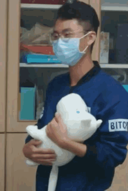a man wearing a mask is holding a stuffed animal that has the word bitc on it