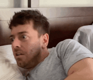 a man with a beard is laying on a bed with his eyes closed .