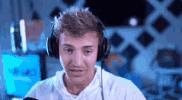 a man wearing headphones is sitting in front of a microphone and making a funny face .