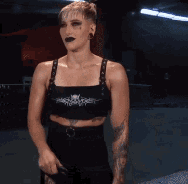 a woman wearing a black crop top with a tattoo on her arm