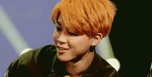 a close up of a person with orange hair and earrings .