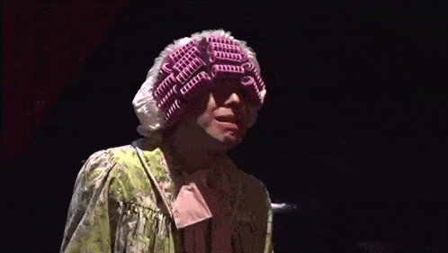 a person wearing a purple and white knitted hat and a green dress