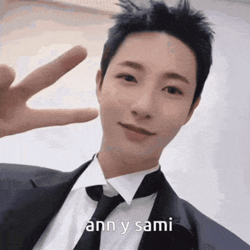 a man in a suit and tie is giving the peace sign