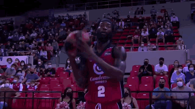 a basketball player in a casademont zaragoza jersey stands in front of a crowd