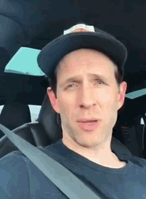 a man wearing a hat is sitting in a car with a seat belt .