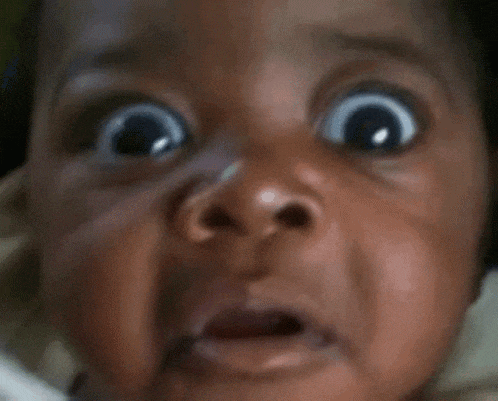 a close up of a baby 's face with a surprised look on his face
