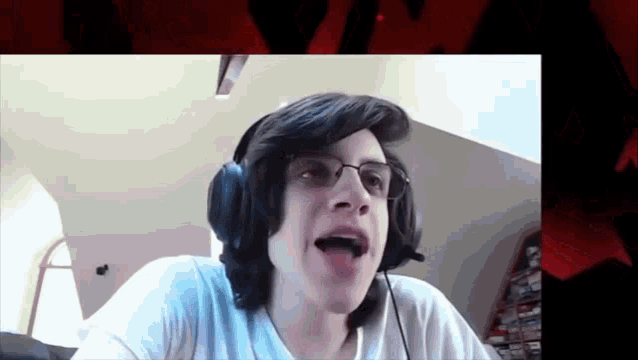 a young man wearing headphones and glasses is talking on a video call .