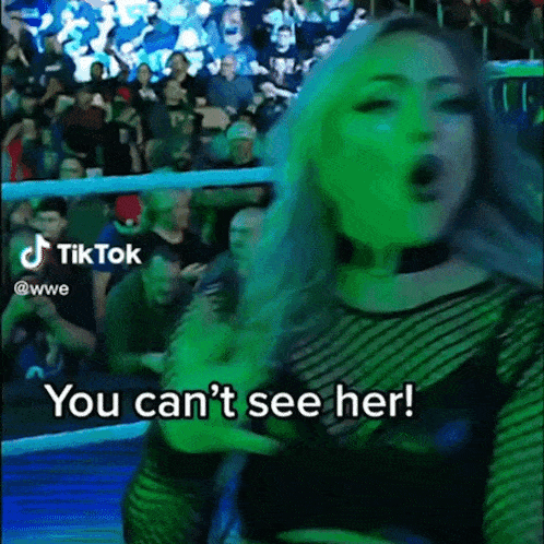 a woman in a wrestling ring says " you can 't see her " in front of a crowd