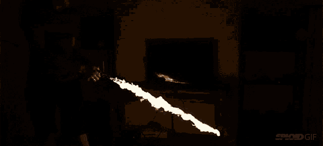 a man is holding a flamethrower in front of a tv screen that says sploid gif on it