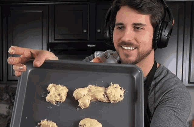 a man wearing headphones holds a tray of cookies