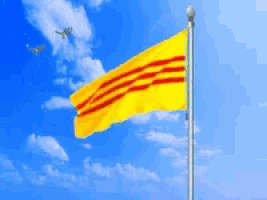 a yellow flag with red stripes flying in the wind