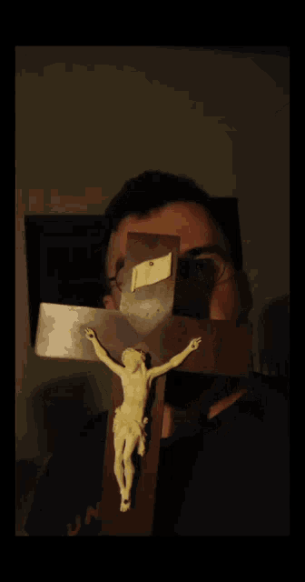 a man with glasses holds a crucifix in front of his face