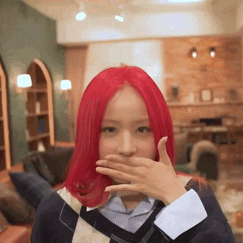 a woman with red hair covers her mouth with her hand